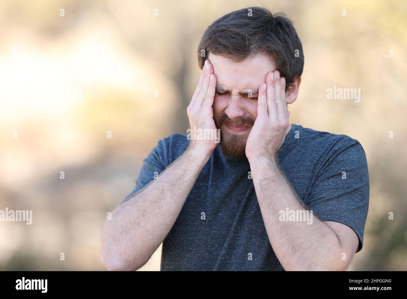 Stressed man suffering migraine attack outdoors Stock Photo