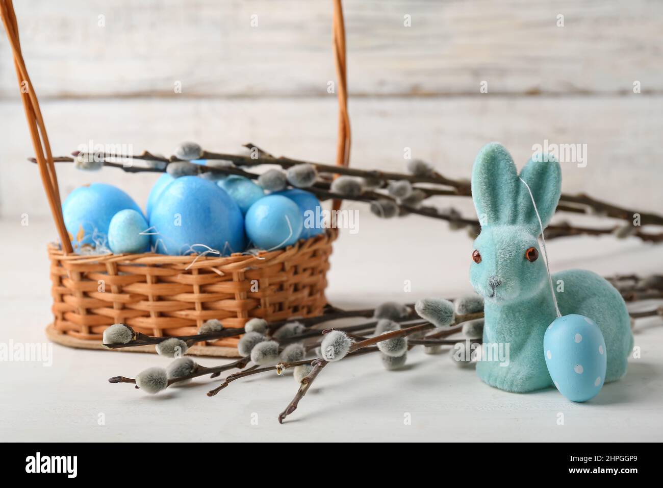 Willow branches, bunny and basket with painted Easter eggs on light ...