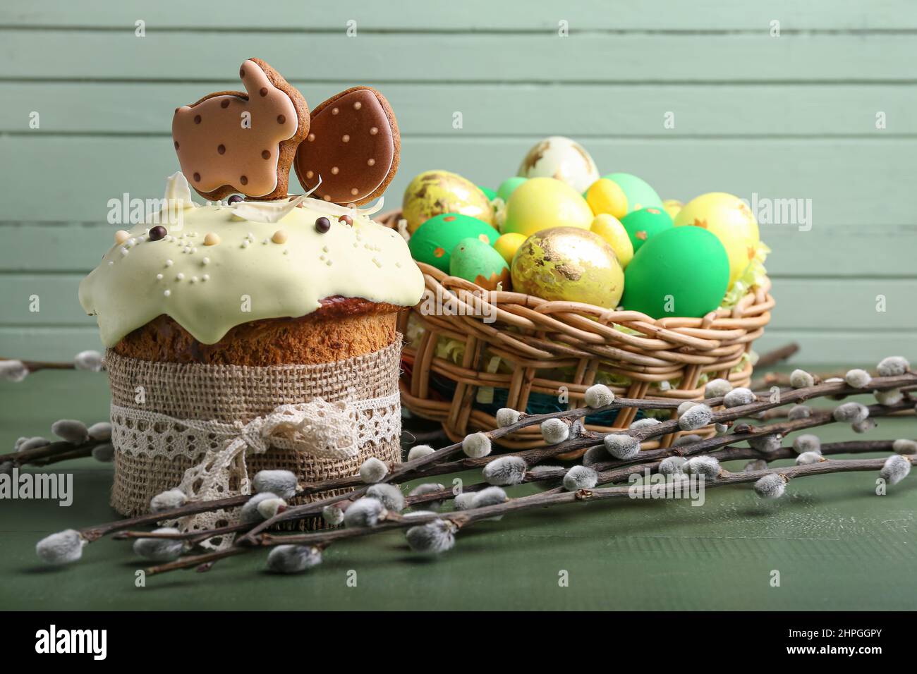 Willow branches, Easter cake and basket with painted eggs on green ...