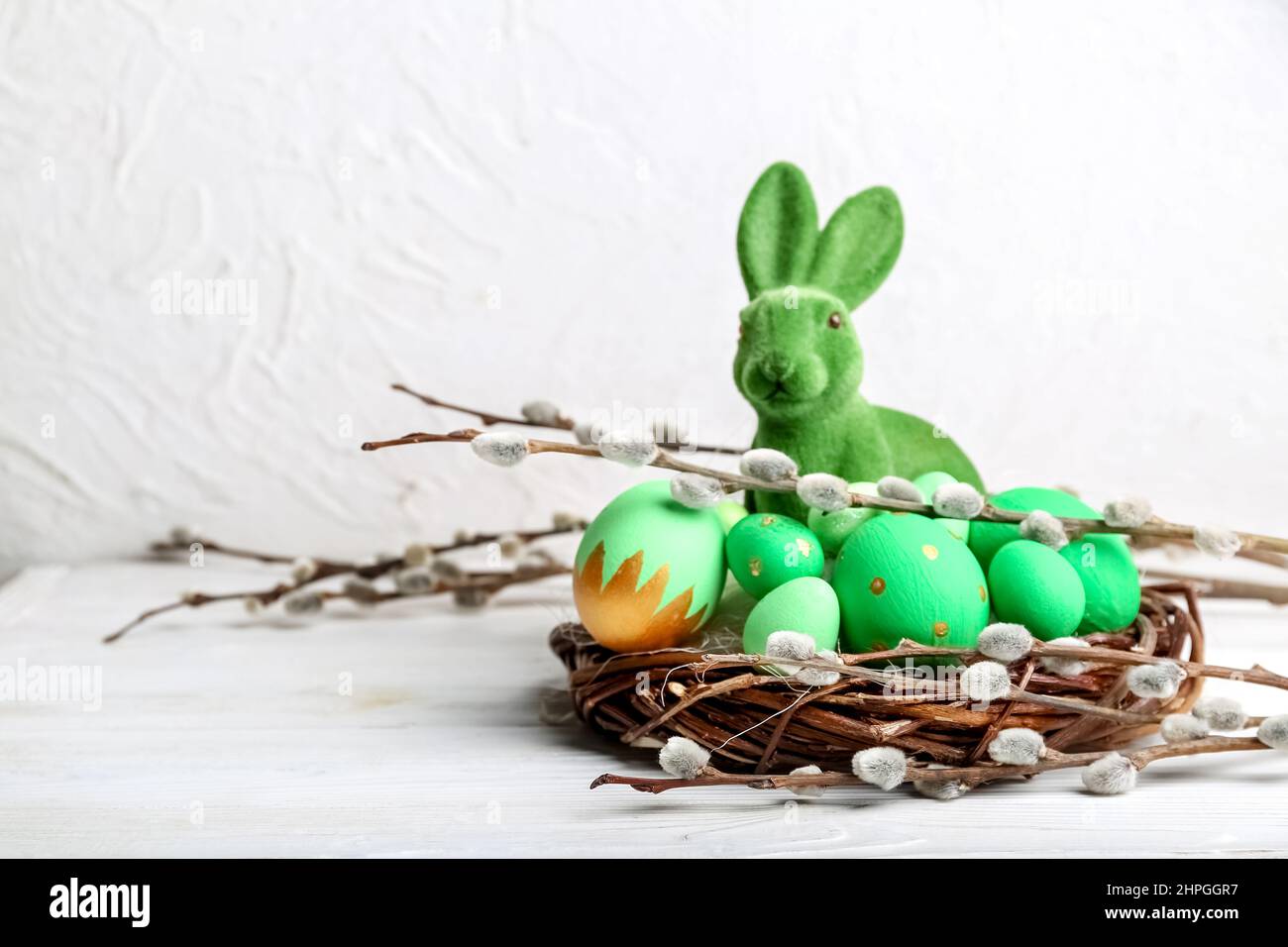 Willow branches, bunny and nest with painted Easter eggs on light ...
