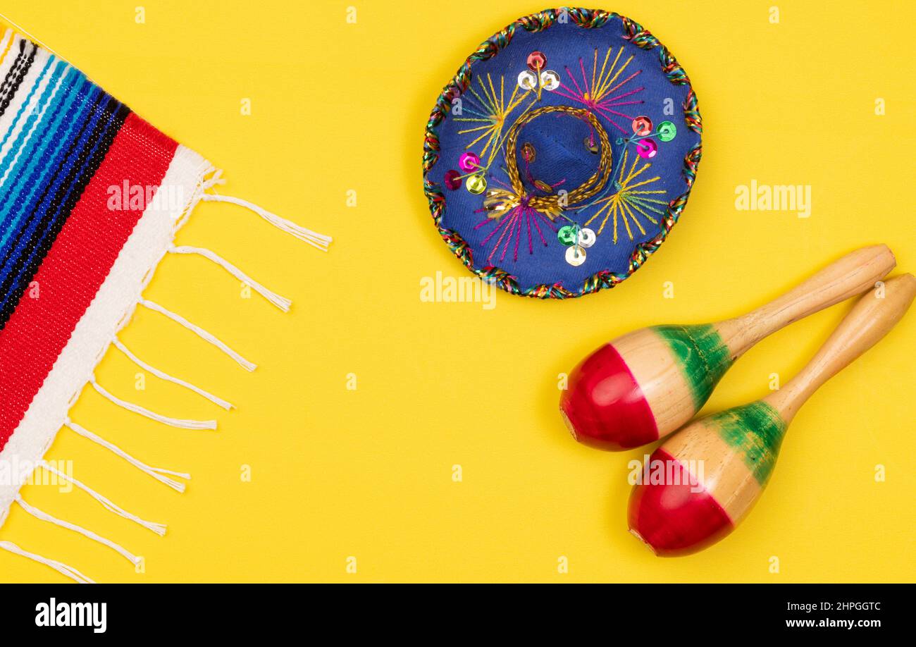 Colorful Cinco de Mayo background with Traditional Mexican Serape, Sombrero and marcas on a yellow background with copy space Stock Photo