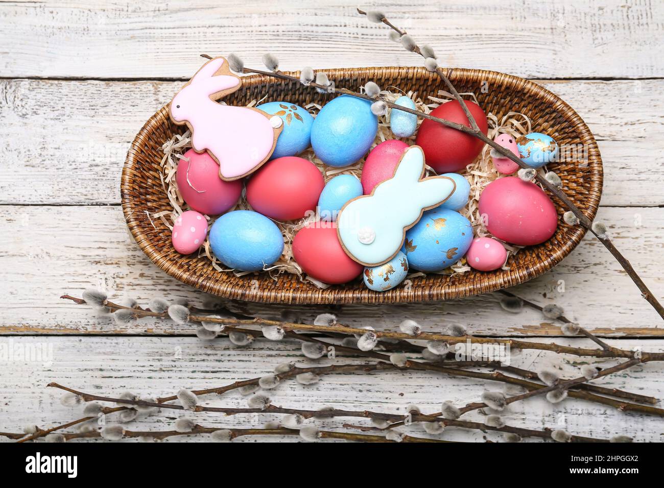 Willow branches, Easter cookies and basket with painted eggs on light ...