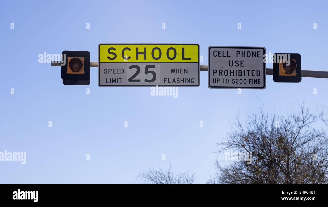 Street sign with warning for school speed limit of 25 mph. Cell phone use prohibited while driving, accident prevention at school zone. Stock Photo