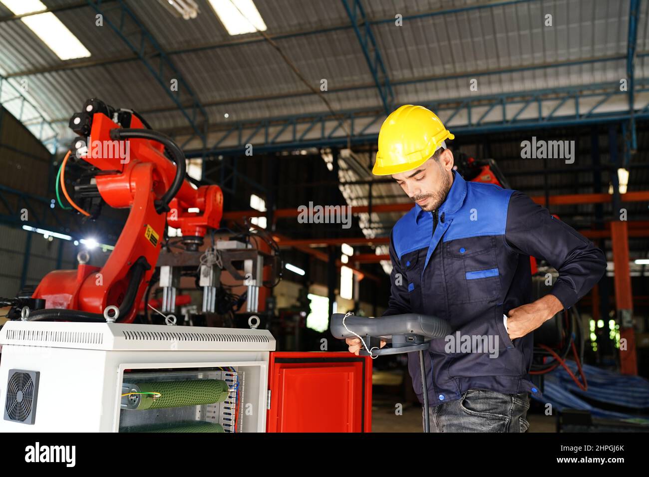 engineer checking control panel and teaching new Automatics robot arm and operating control machine in factory. Stock Photo