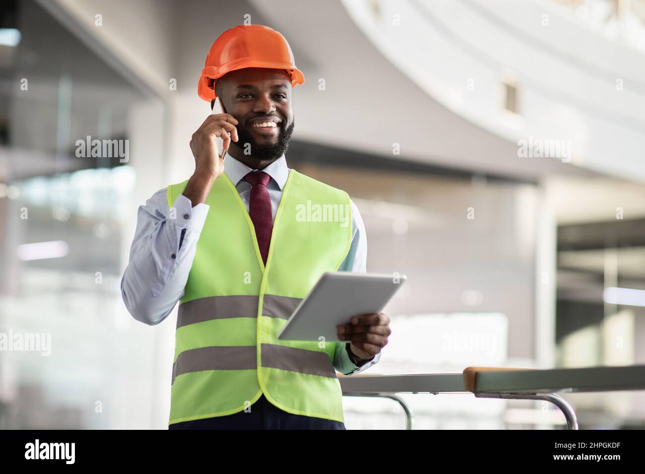 Happy african american architect having phone conversation, using digital tablet Stock Photo