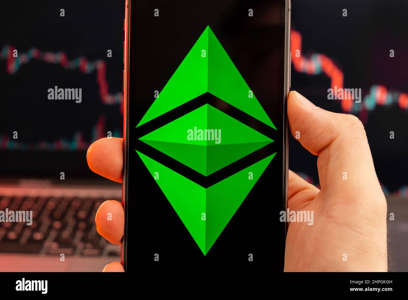 Ethereum Classic ETC app of cryptocurrency stock market analysis on the screen of mobile phone in man hands and downtrend charts trading data on the background, February 2022, San Francisco, USA. Stock Photo