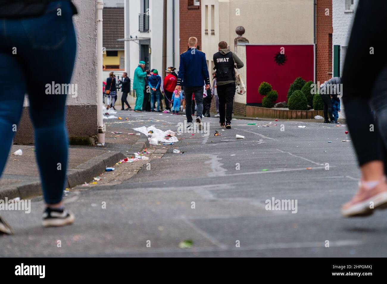 Bornheim, North Rhine-Westphalia, Germany - February 22, 2020: People walking along a street, dumped with trash, after a carnival parade. Stock Photo