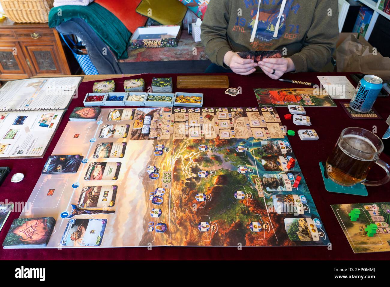 Two friends, 36 and 40, playing the board game Lost Ruins of Arnak on a tabletop and enjoying a couple of beers, UK Stock Photo