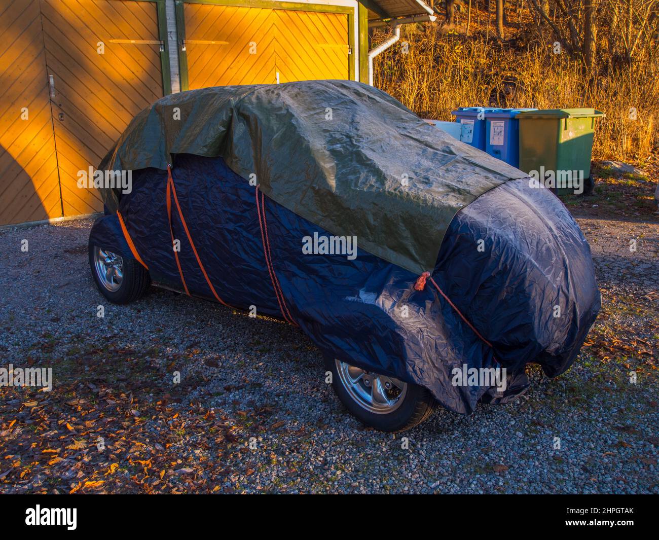 Tarp covered car in front of garage Stock Photo Alamy