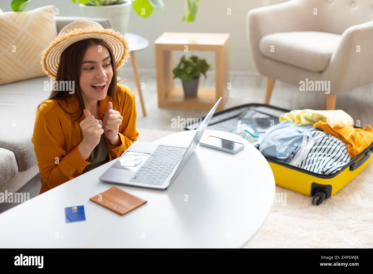 Excited young woman booking tourist trip online on sale, getting discount on hotel reservation or plane tickets at home Stock Photo