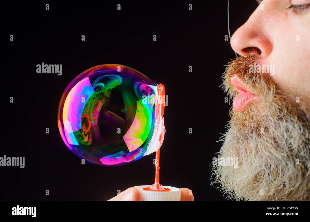 Bearded man blowing soap bubbles. Play with bubbles. Happiness. Good mood. Childhood. Closeup. Stock Photo