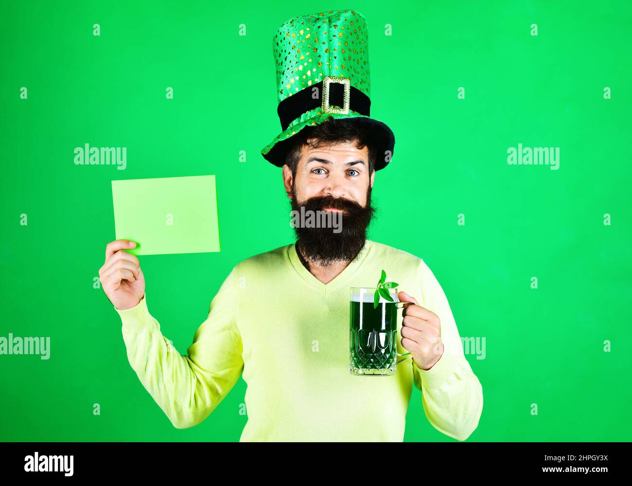 Bearded man in hat with billboard and mug of beer. Patricks Day celebration. Four leafed clover. Stock Photo
