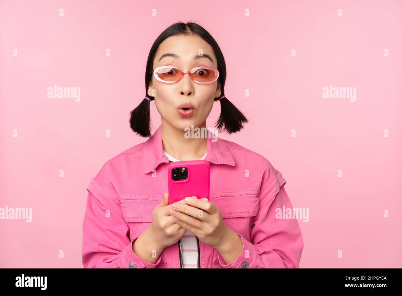 Portrait of korean girl in stylish sunglasses holding mobile phone