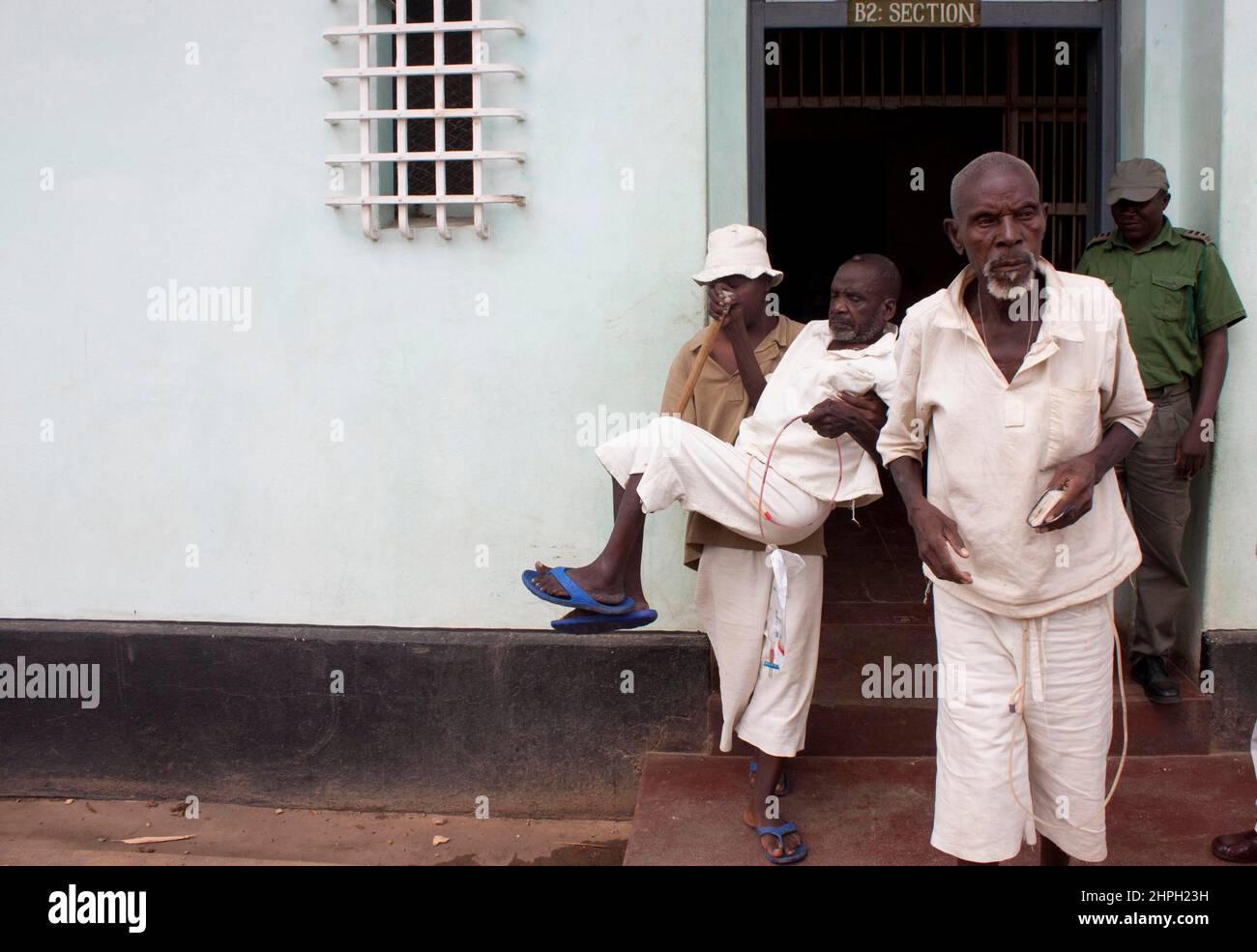 A seriously ill inmate at the Harare Central Prison is carried by another inmate. He was one of many convicts who were being released on grounds of their ill-health. Zimbabwe. Stock Photo