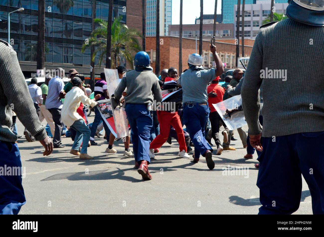 Police officers with baton sticks assault opposition MDC members at Harare Central Business District. The opposition members had been holding a peaceful march when the police began assaulting them. Zimbabwe. Stock Photo