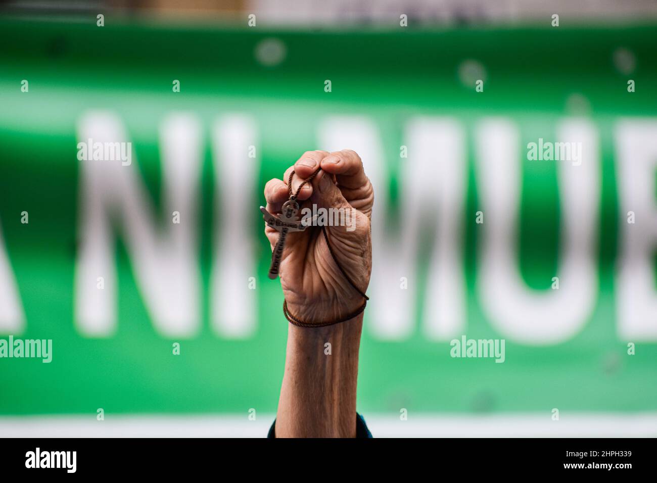 A Anti-abortion demonstrator protests with a cross necless on her hand as both Pro-Choice and anti-abortion movements protest outside in support and against the decriminalization of abortions from the penal code, outside the Constitutional Court in Bogota, Colombia on February 21, 2022. Stock Photo