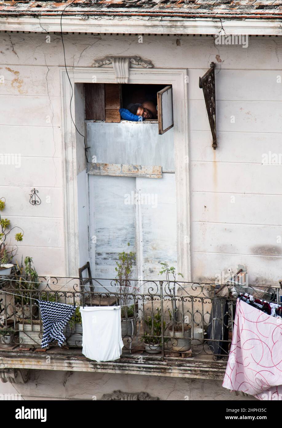 Man asleep in window of his apartment building in Havana, Cuba. Stock Photo