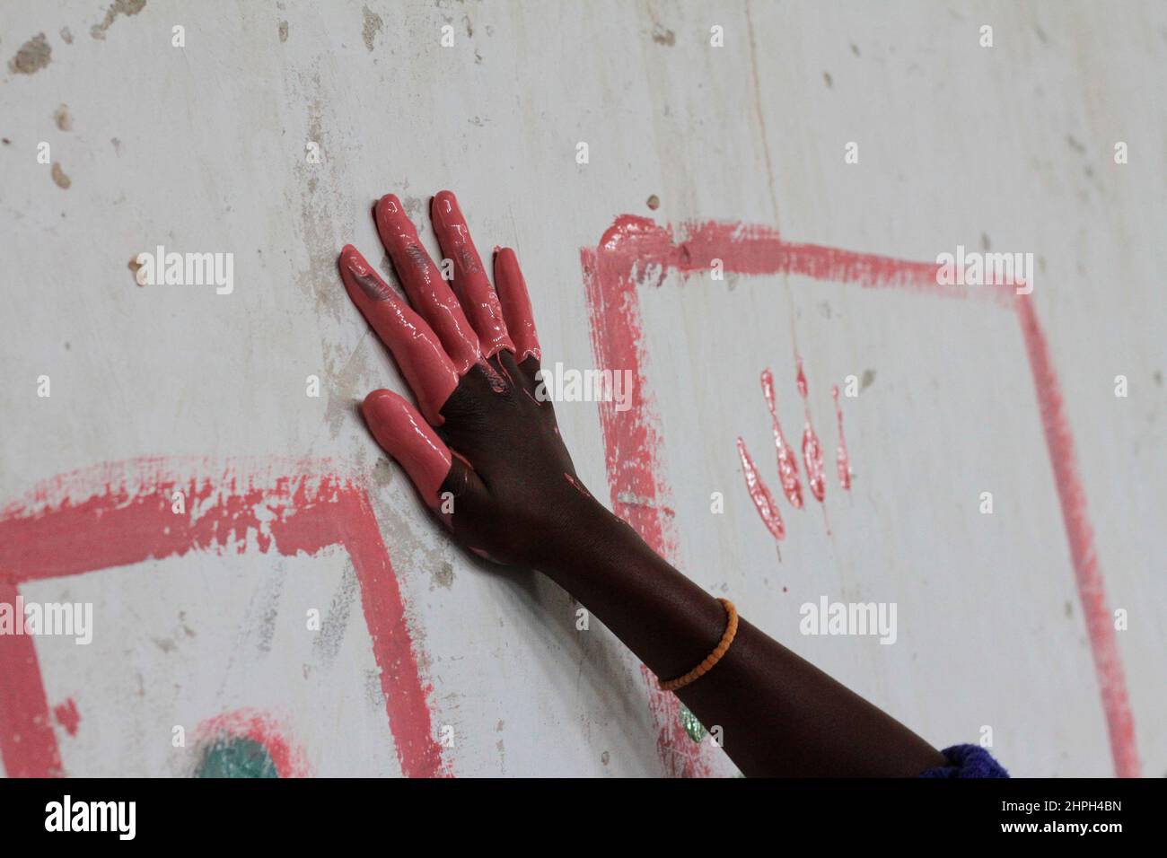 A hand is seen drawing on the wall at Macheke Primary School. The children were given a chance to paint anything they wanted on the walls of the school hall. Zimbabwe. Stock Photo