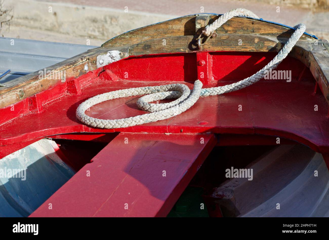 Red wooden rowing boat with a rope lying on the seatboard Stock Photo