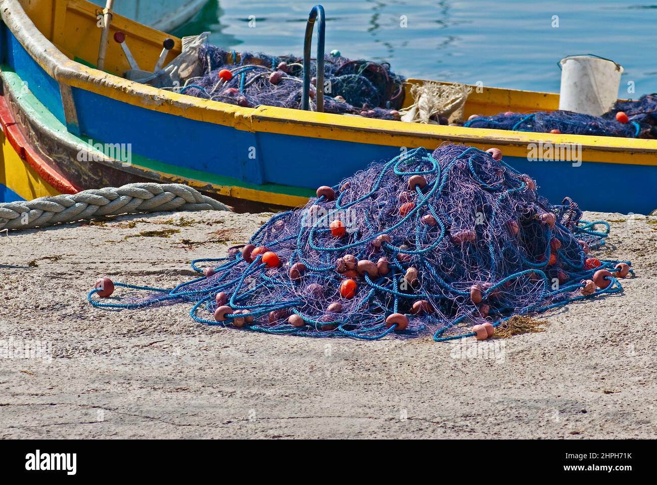 Blue fishing net in front of a richly colored boat on the island Malta. Stock Photo
