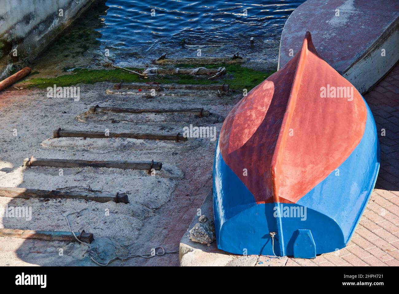 Blue boat laying upside down in a small harbor on the island Malta. Stock Photo