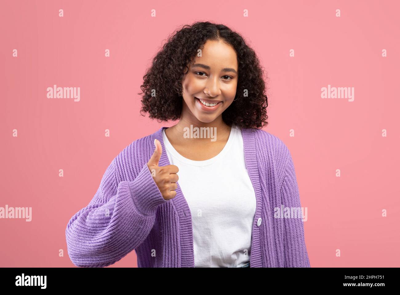 Attractive young African American woman showing thumb up gesture, recommending or approving something Stock Photo