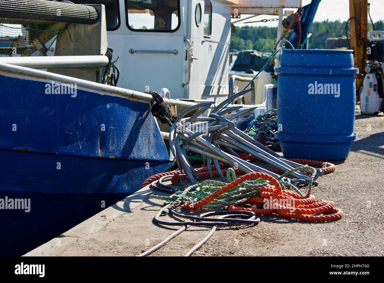 Fishing equipment on the quay in front of an industrial fishing boat in a harbor. Stock Photo