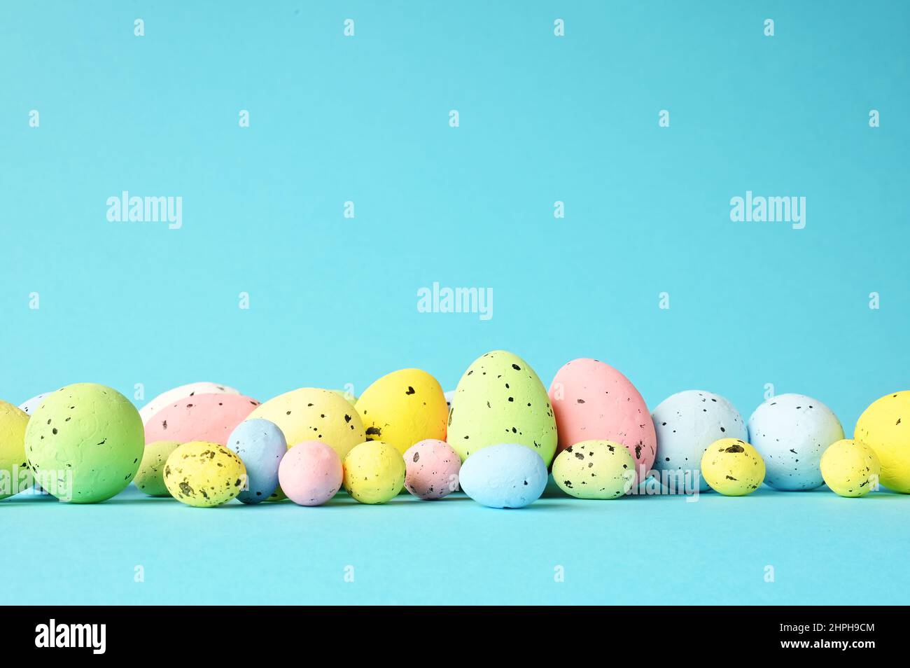 Row of painted colored easter eggs on blue background. Happy Easter background. Stock Photo