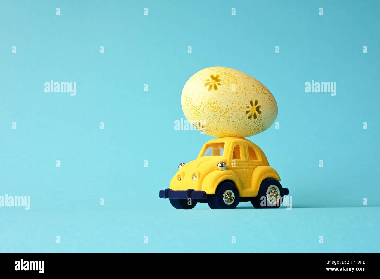 One Easter egg on a small car on a blue background. Copy space. Easter card. Stock Photo