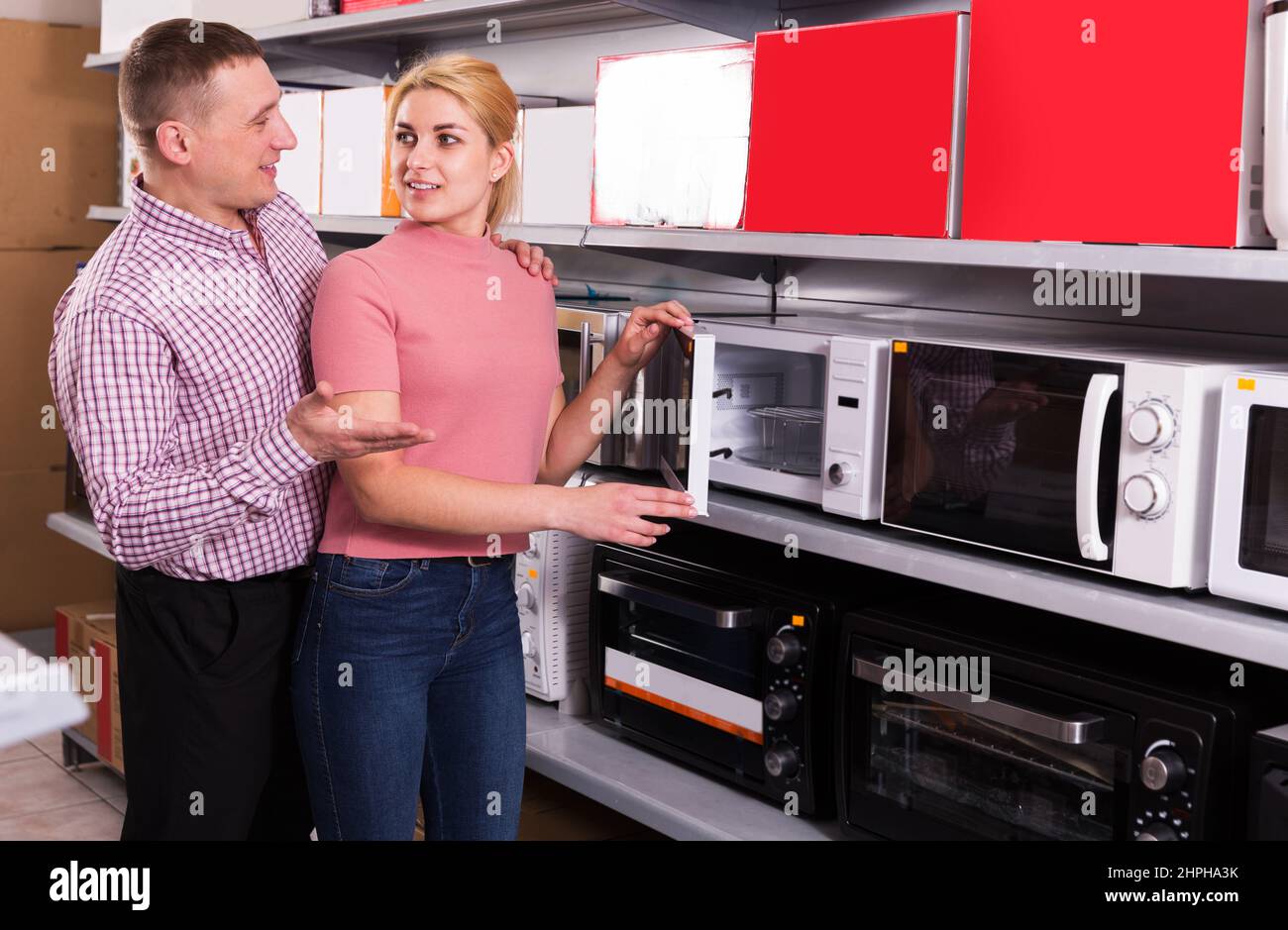 happy couple choosing new microwave for kitchen in furniture store Stock Photo