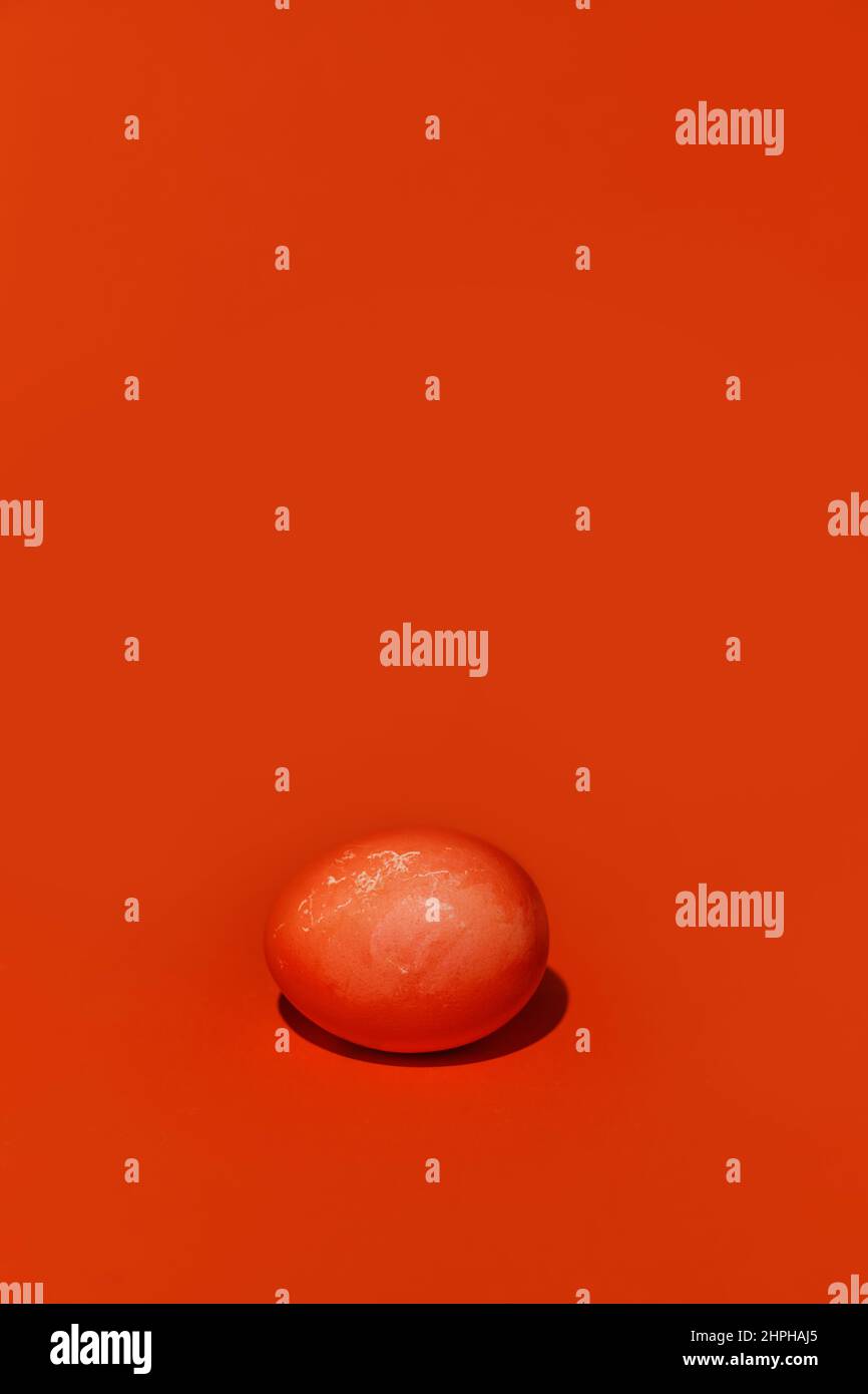 A painted Easter egg of red color on a red background. With space to ...