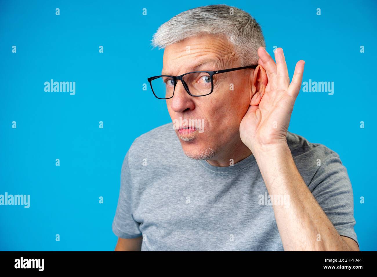 Middle age man over iblue background with hand over ear listening Stock Photo