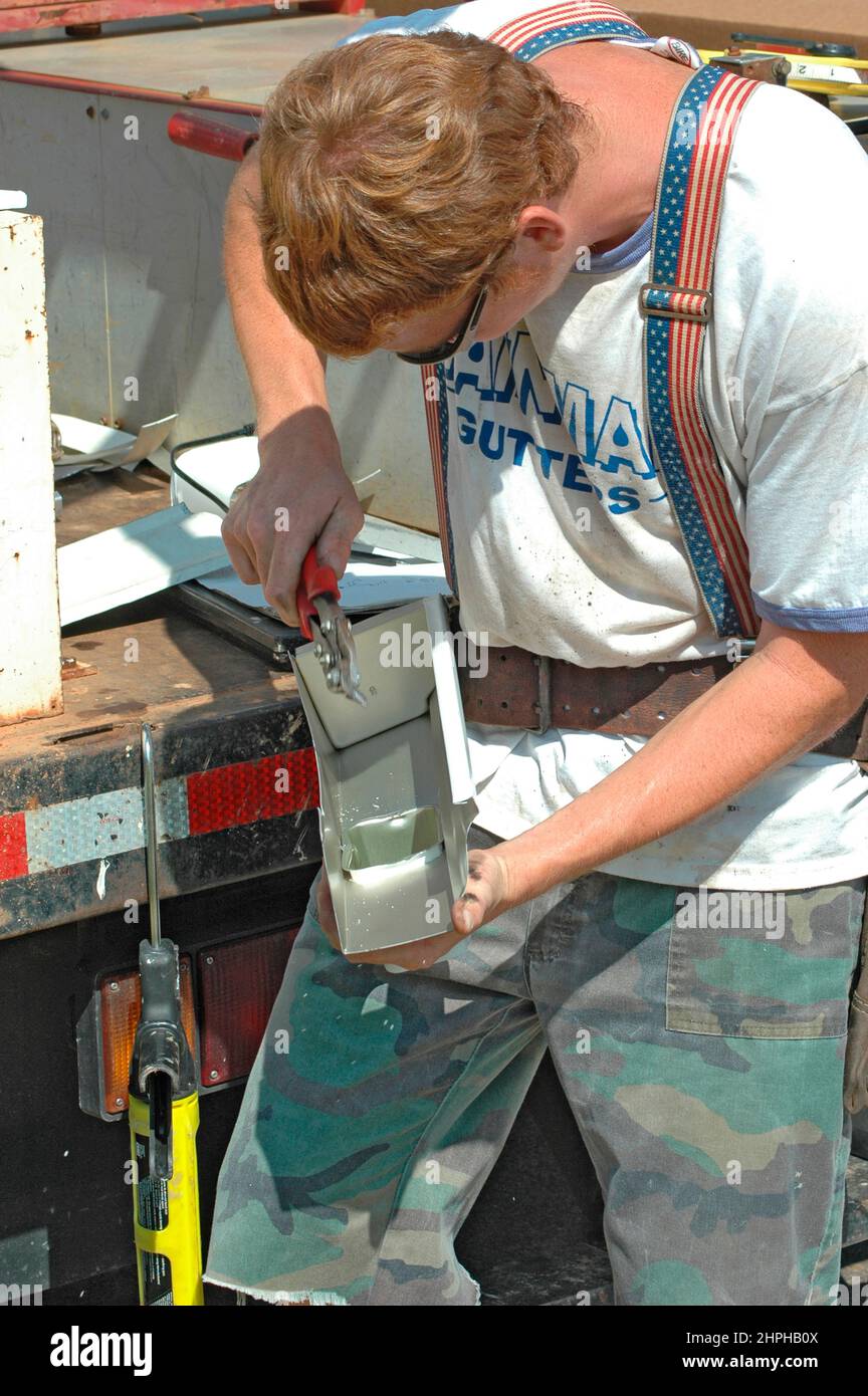Installation of rain water run off gutters by young men on ladders and