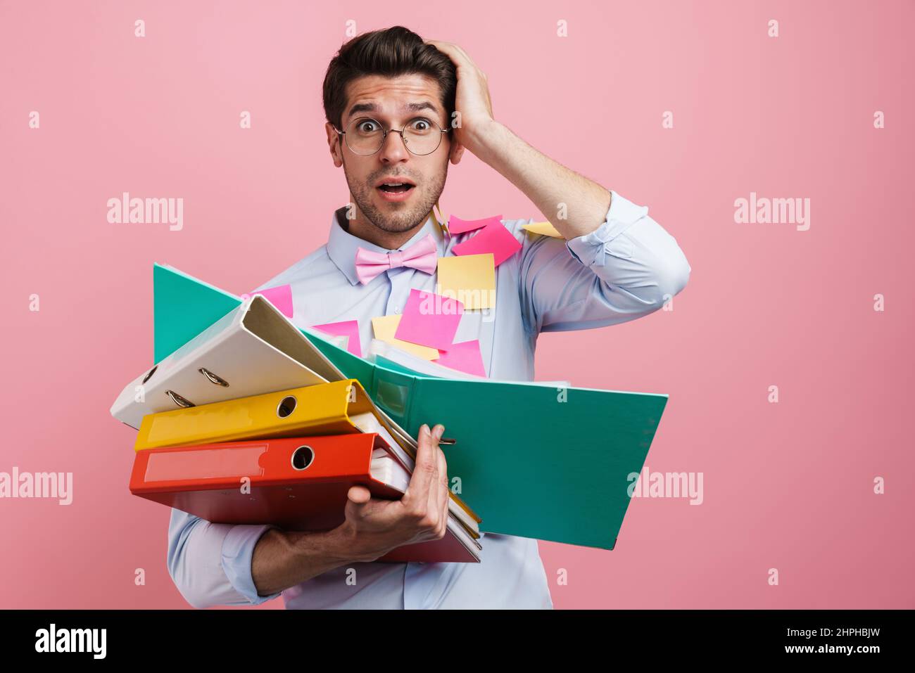 Young white shocked man with stickers posing with document cases isolated over pink background Stock Photo