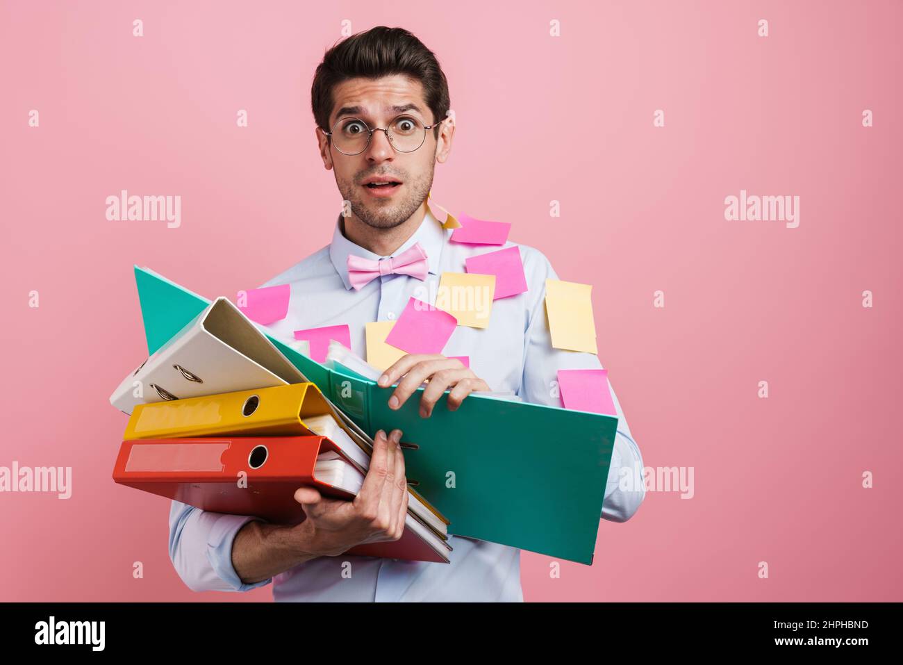 Young white shocked man with stickers posing with document cases isolated over pink background Stock Photo