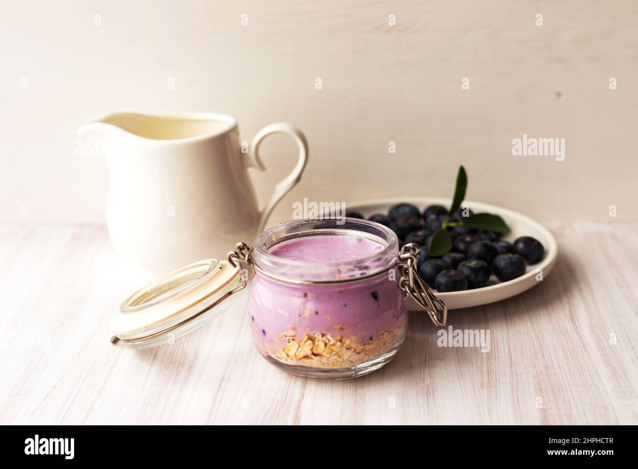 Oatmeal flakes granola or muesli with yogurt smoothie, fresh blueberry and ceramic jug milk Stock Photo