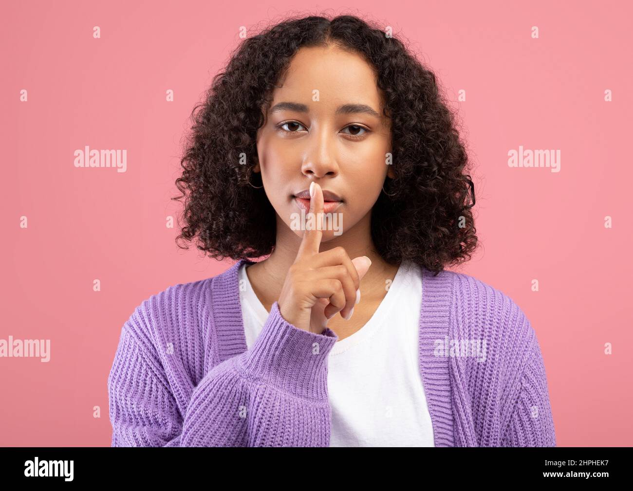 Shh, keep silence, confidential information. Young African American woman gesturing hush on pink studio background Stock Photo