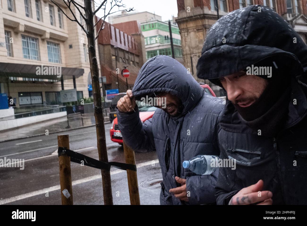 Two men make their way along a wet and windy London street during a rain shower Stock Photo