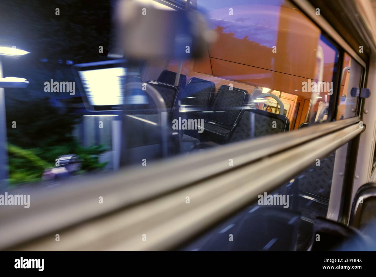 Train car window view with empty chairs reflected in the foreground and blurry dark landscape in the background Stock Photo