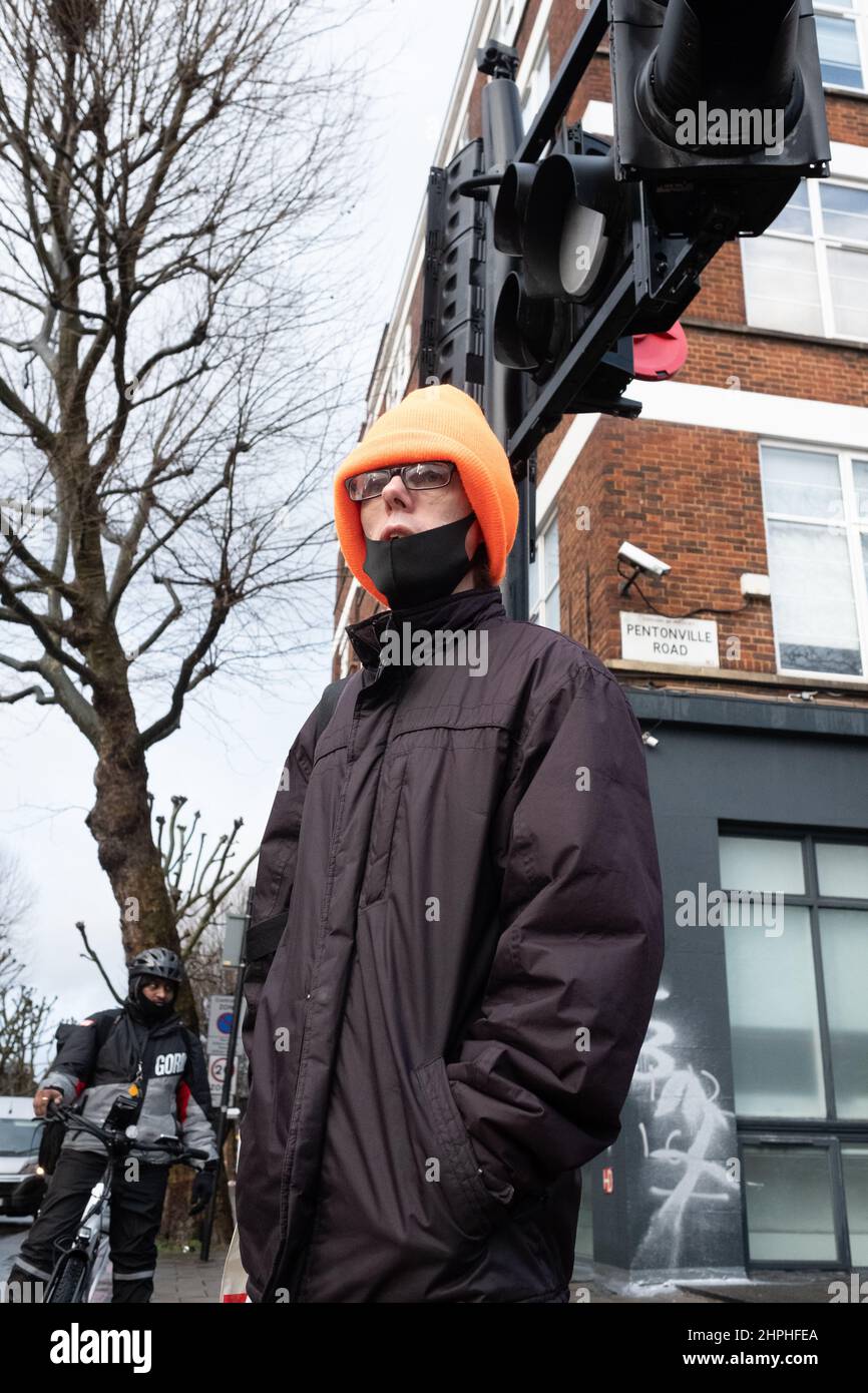 Man in an orange woolly hat waits patiently to cross the road near Kings Cross, London UK Stock Photo