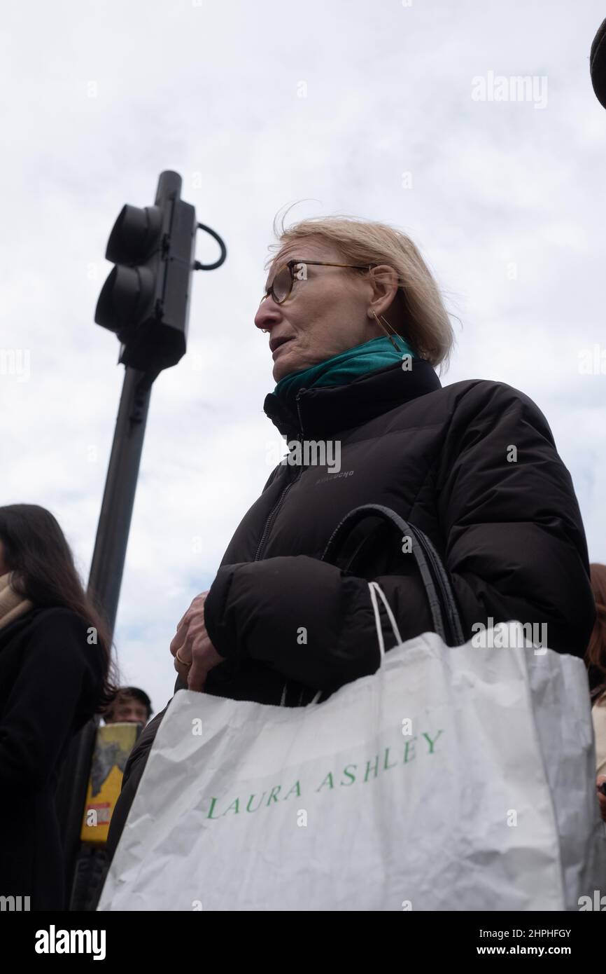 Mature female waits to cross the road carrying a Laura Ashley bag, London UK Stock Photo