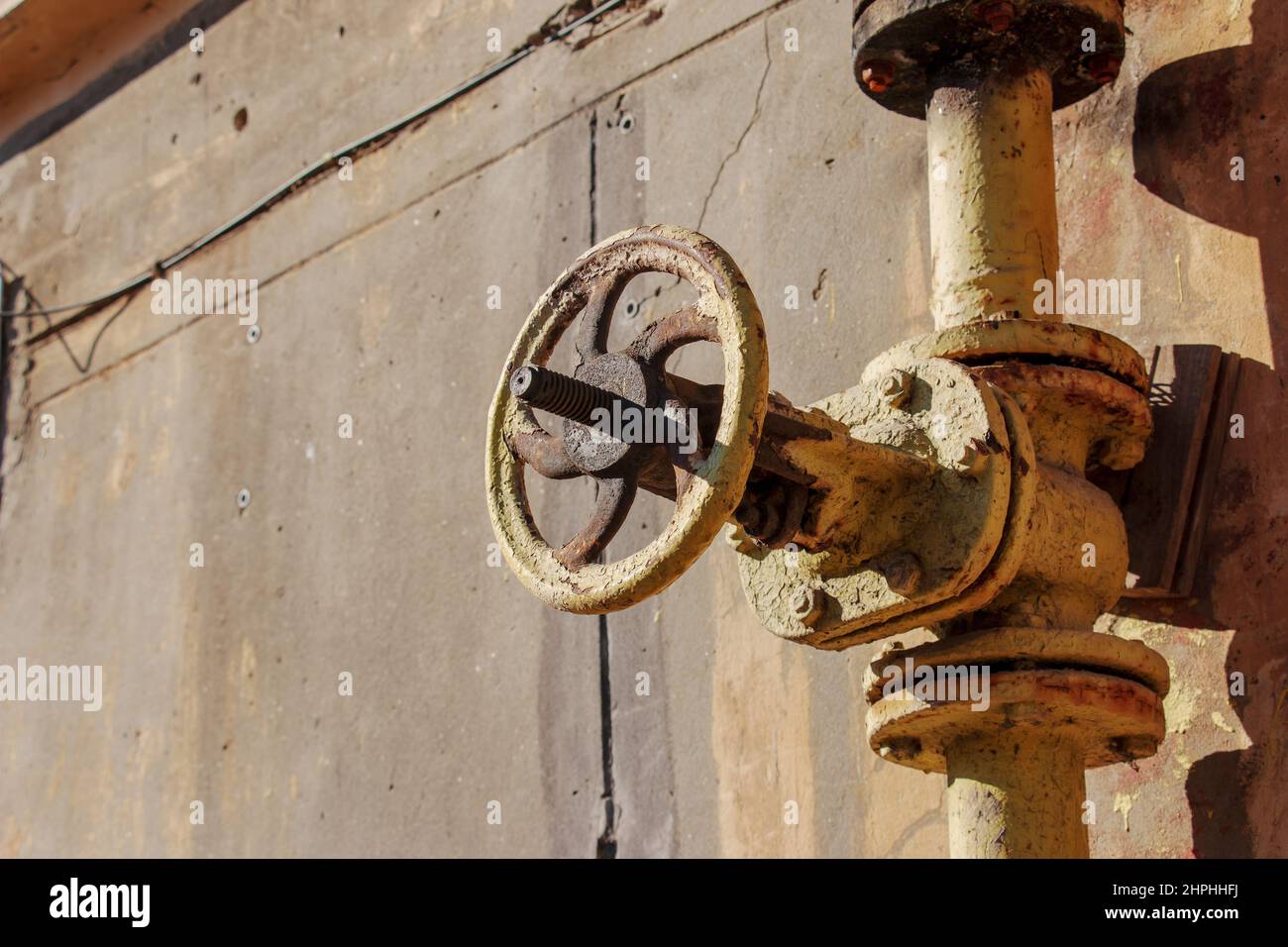 Old rusty gas control valve on the wall. An industrial valve in a large system. The gas transmission system of Ukraine is failing. Stock Photo