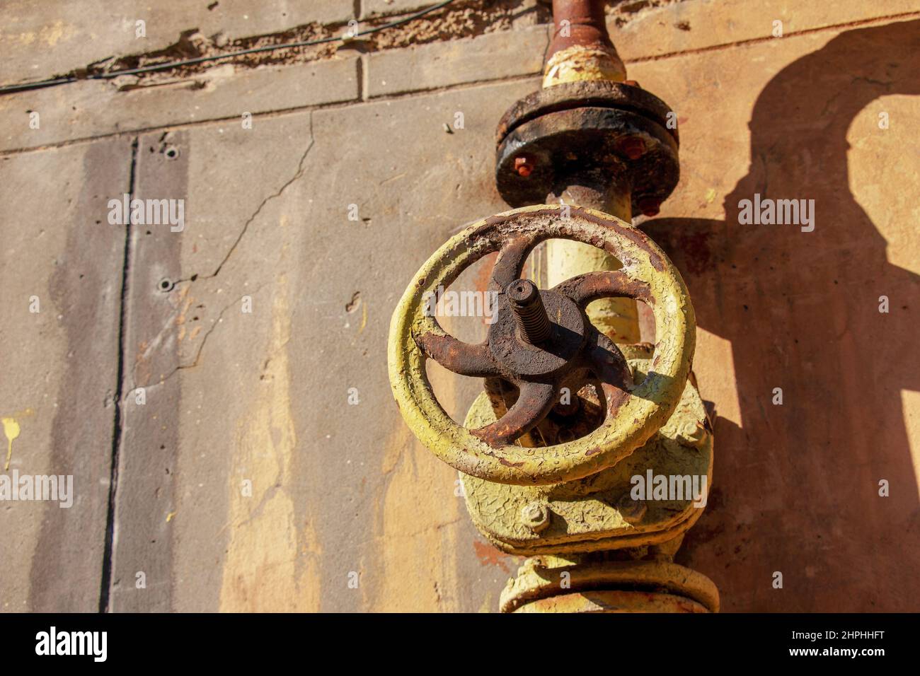 Old rusty gas control valve on the wall. An industrial valve in a large system. The gas transmission system of Ukraine is failing. Stock Photo