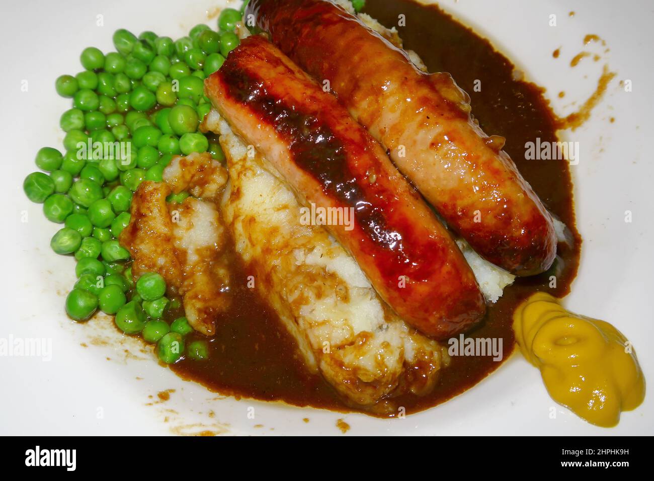 Bangers and Mash with green peas covered in Gravy Stock Photo Alamy