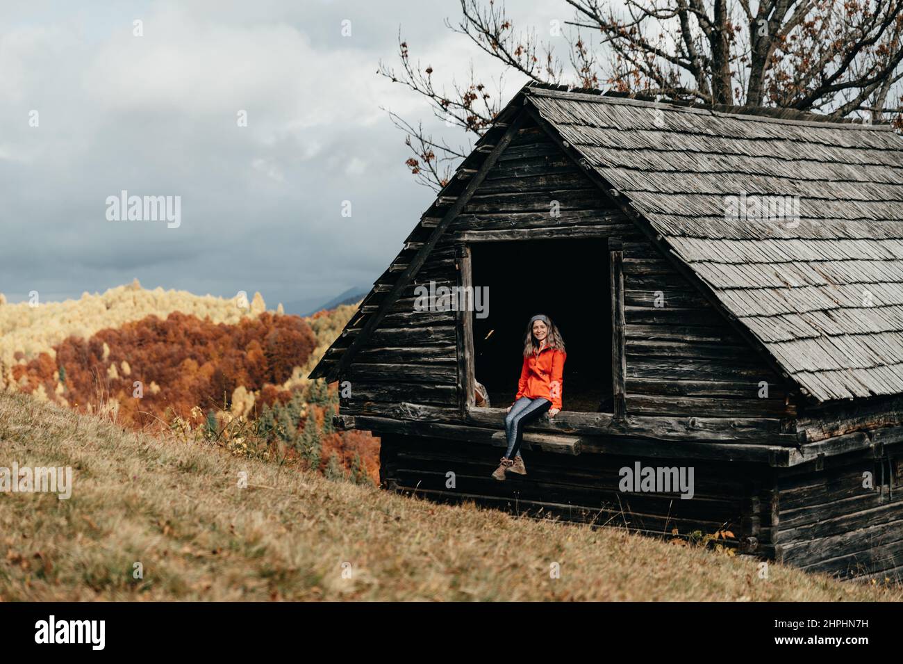 Happy young girl sitting on a barn in the mountains during autumn Stock ...