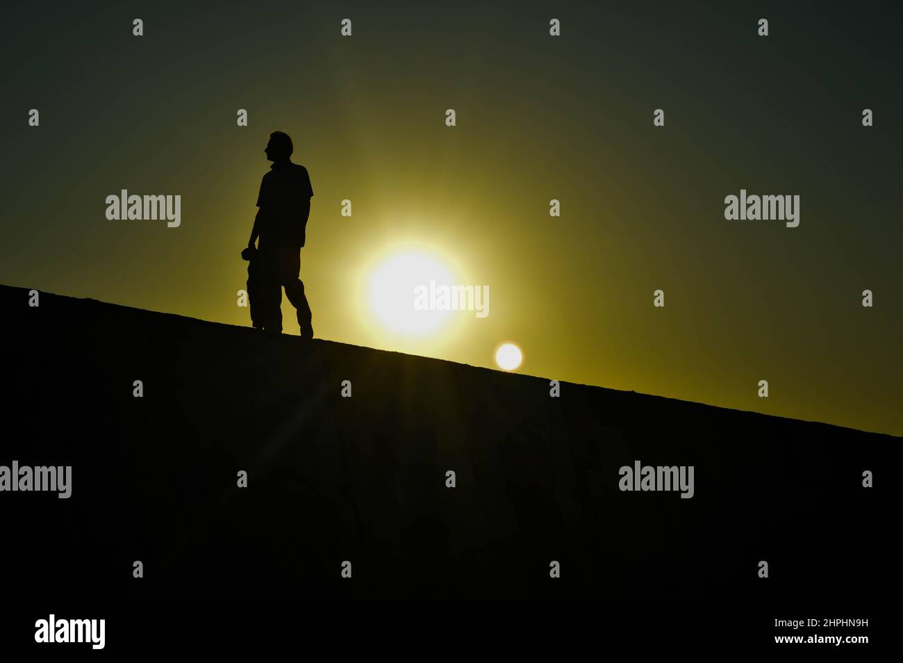 Silhouette of man walking at sunset Stock Photo - Alamy