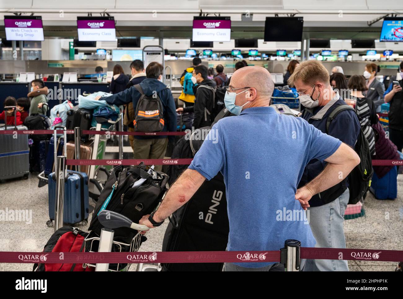 Hong Kong, China. 21st Feb, 2022. Passengers wait in a line for Qatar  Airways airline check-in counter at Hong Kong's Chek Lap Kok International  Airport. Hong Kong is notoriously known for having