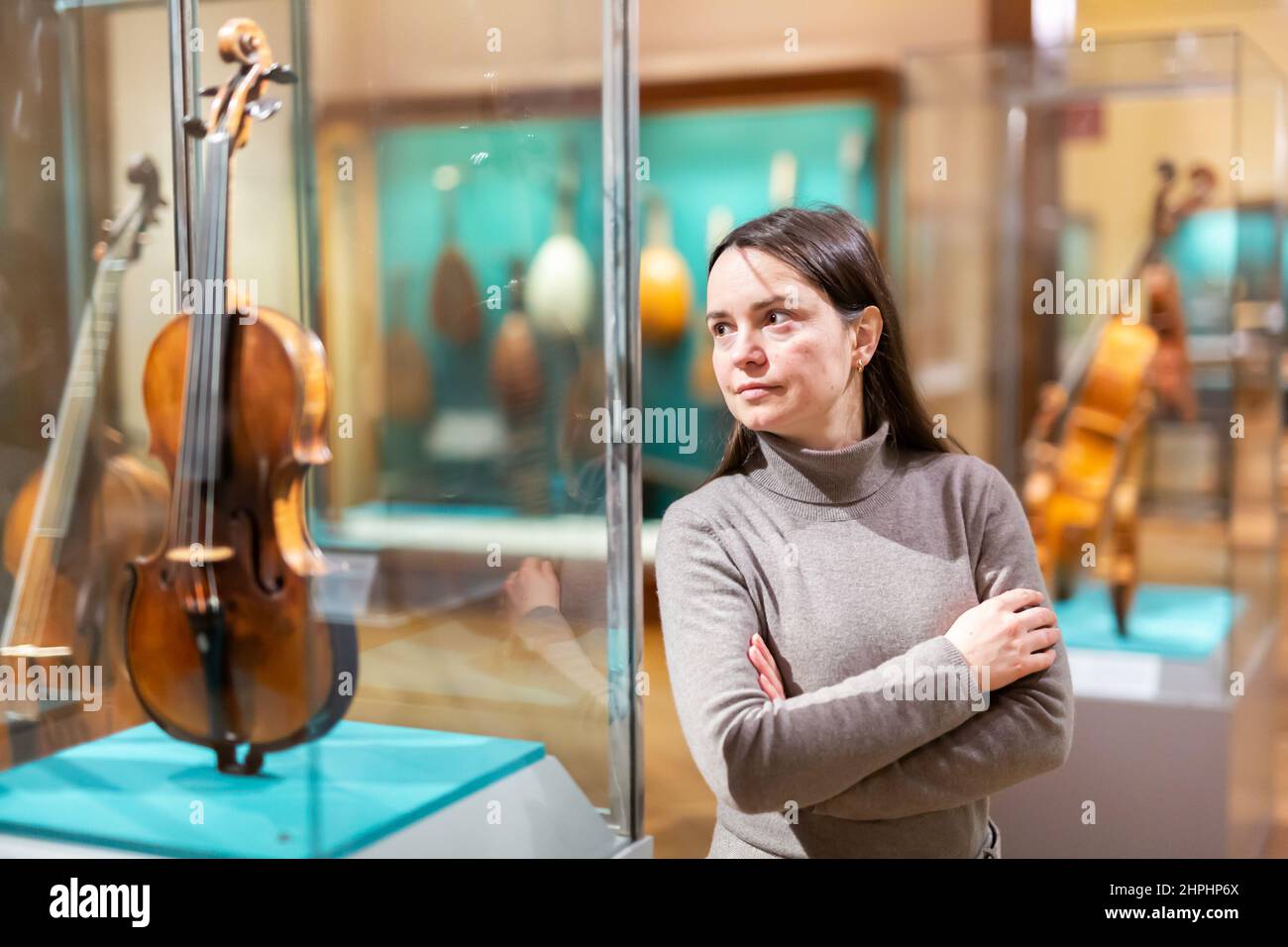 Female museum visitor examining ancient musical instruments Stock Photo