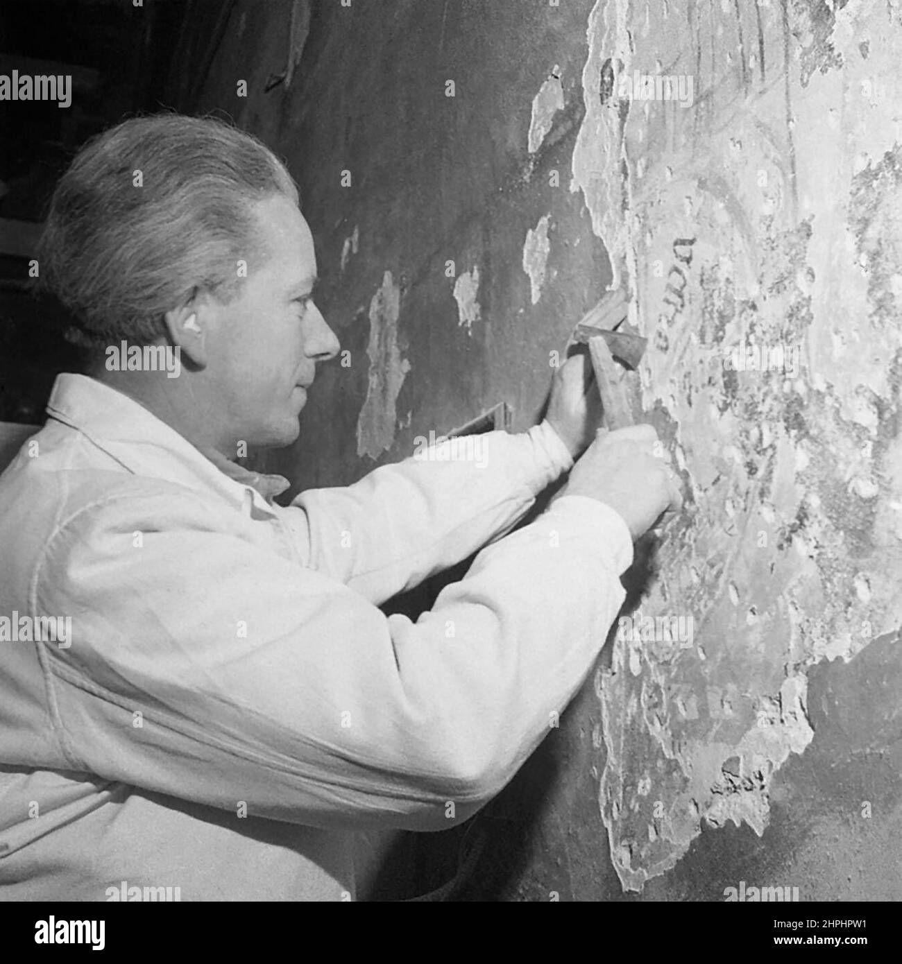 The artist Bruno Malanik uncovering gothic frescoes in the civic hospital church of St. Blasius in Salzburg ca.  December 1948 Stock Photo