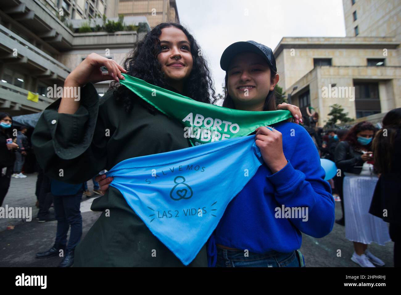 A pro-choice and a Anti-abortion activists pose toghether as their movements protest outside in support and against the decriminalization of abortions from the penal code, outside the Constitutional Court in Bogota, Colombia on February 21, 2022. Abortions were decriminalized after 8 hours of debate leading now access for pregnant women to access them up to week 24. Stock Photo